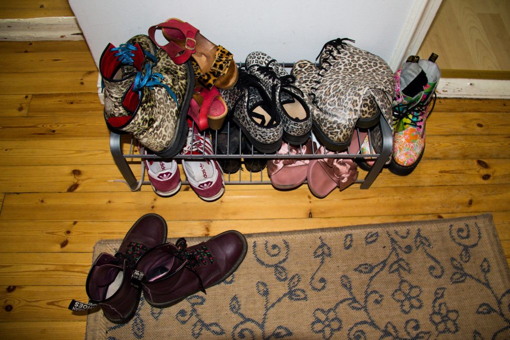 Kuvassa on monenlaisia kenkiä. Saappaita ja sandaaleja eteisessä. Moni on värikäs ja niissä on leopardikuosia.