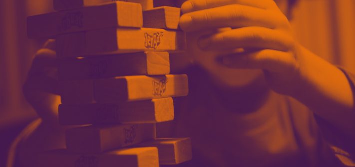 Kuvassa lapsi pelaa puupalikoista koostuvaa peliä huojuvaa tornia.