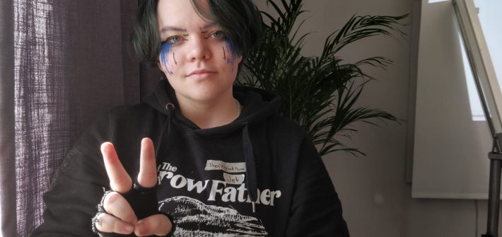 Mustaan pitkähihaiseen ja kynsikkäisiin pukeutunut mustatukkainen Jet, jolla on paljon sinimustaa meikkiä silmien alla.