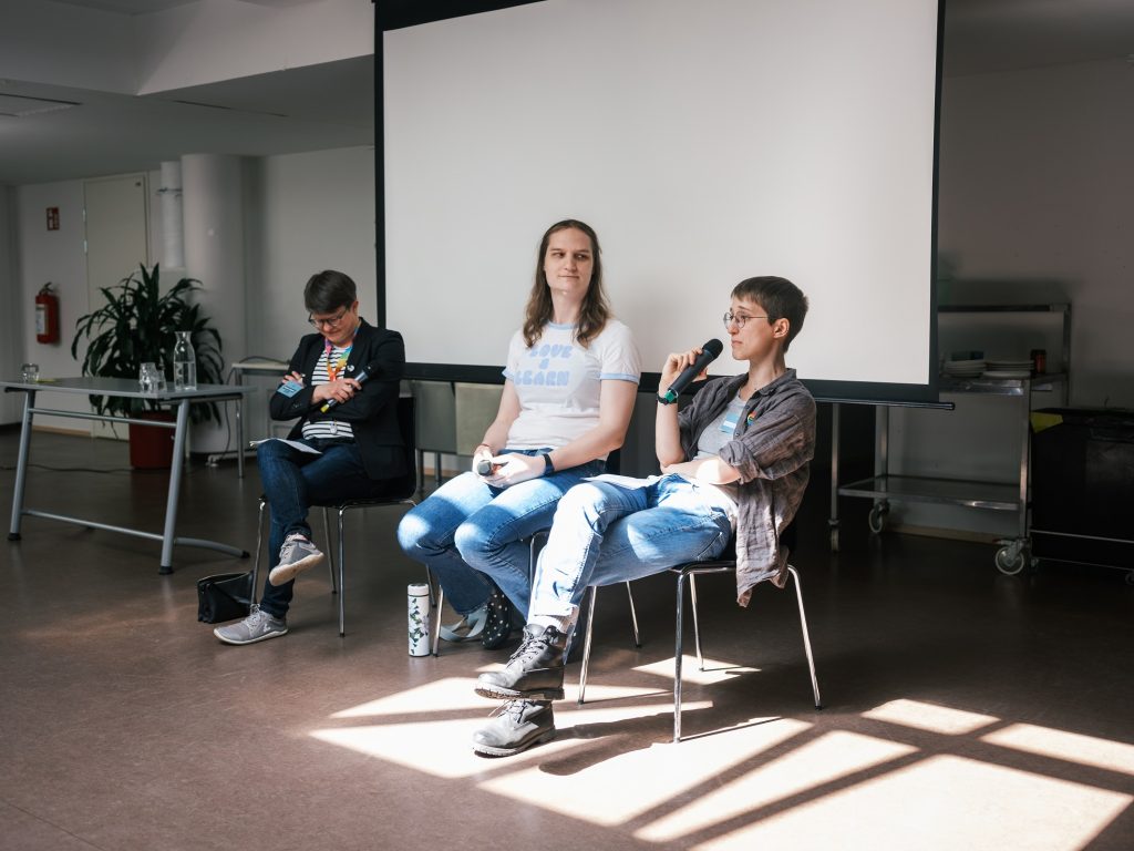 Ilaria Todde istuu rennosti tuolilla ja puhuu mikrofoniin. Hänen veirellään Emilia Blåsten ja Kerttu Tarjamo.