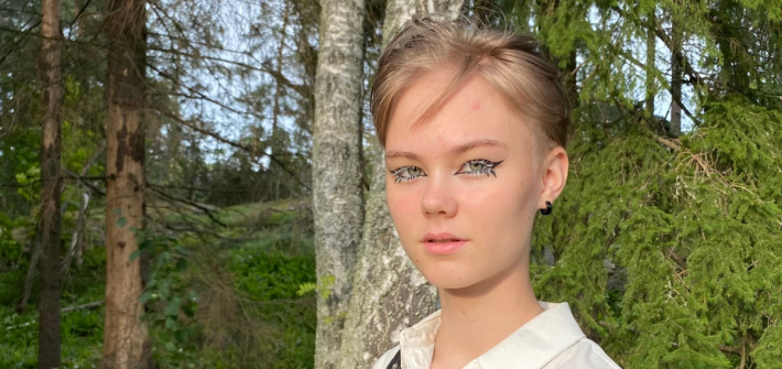 Setan nuorisotoimikunnan puheenjohtaja Saara Katainen. Hänellä on lyhyet hiukset, voimakas silmämeikki, valkoinen kauluspaita ja hän seisoo metsäisen tausta edessä.