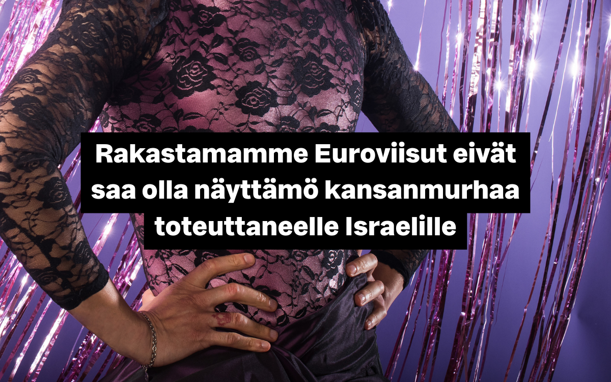 Maskuliininen henkilö mustassa pitsipaidassa kädet vyötäisillä. Taustalla on kimaltelevia koristeita.