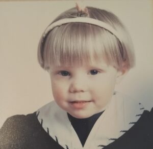 Kuvassa Remi lapsena. Lapsi hymyilee, päässä on hiuspanta.